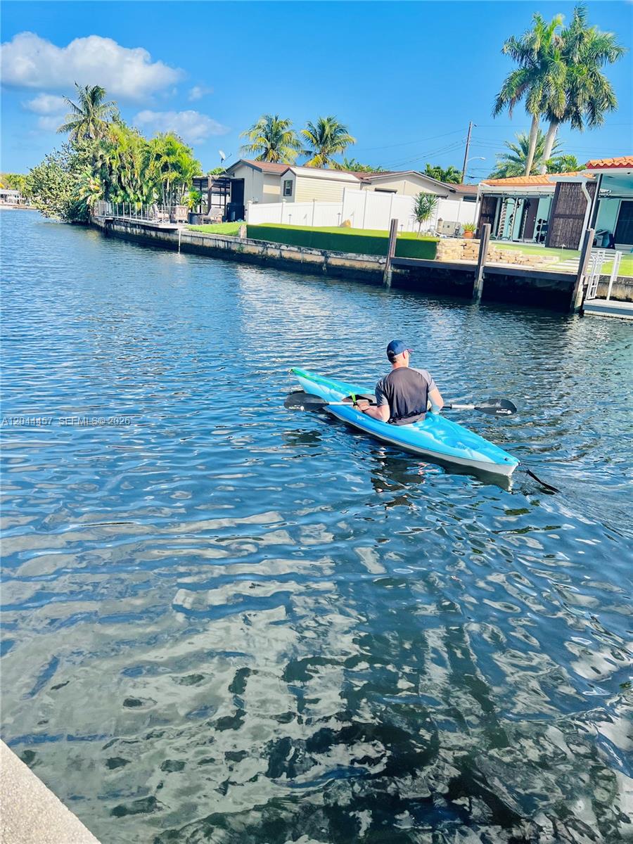 A person paddles a blue kayak along a canal lined with houses and palm trees — OAKLAND PARK, FL