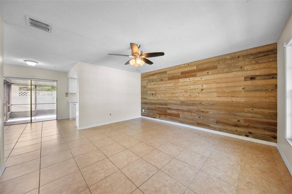 A living room features beige tile flooring, a ceiling fan, and a wood-plank accent wall — 142 BAYBERRY COURT, WINTER SPRINGS, FL