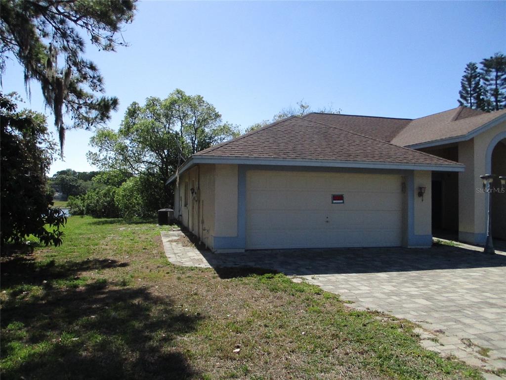 A view of a house exterior featuring a two-car garage and a paved driveway — 8904 PLANTERS LANE, NEW PORT RICHEY, FL