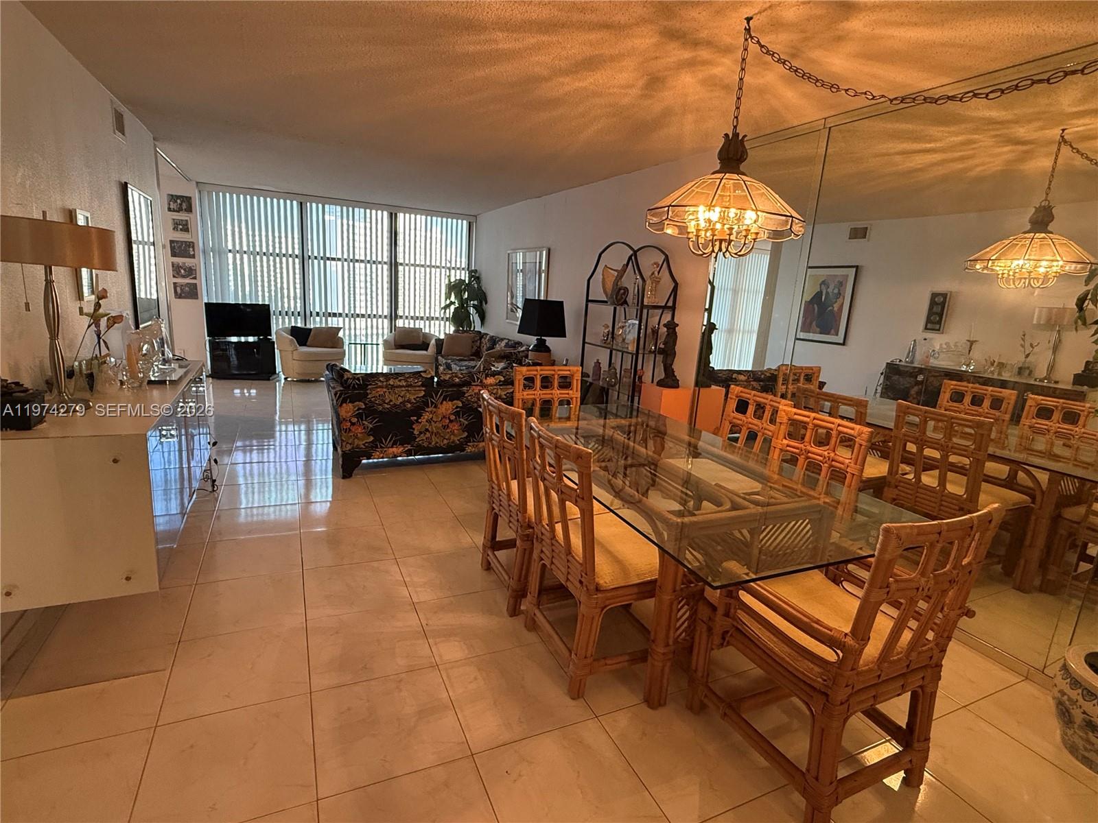 A dining area with a glass-topped rattan table sits before a large mirrored wall — 1000 Parkview Dr # 1022, Hallandale Beach FL 33009, HALLANDALE BEACH, FL