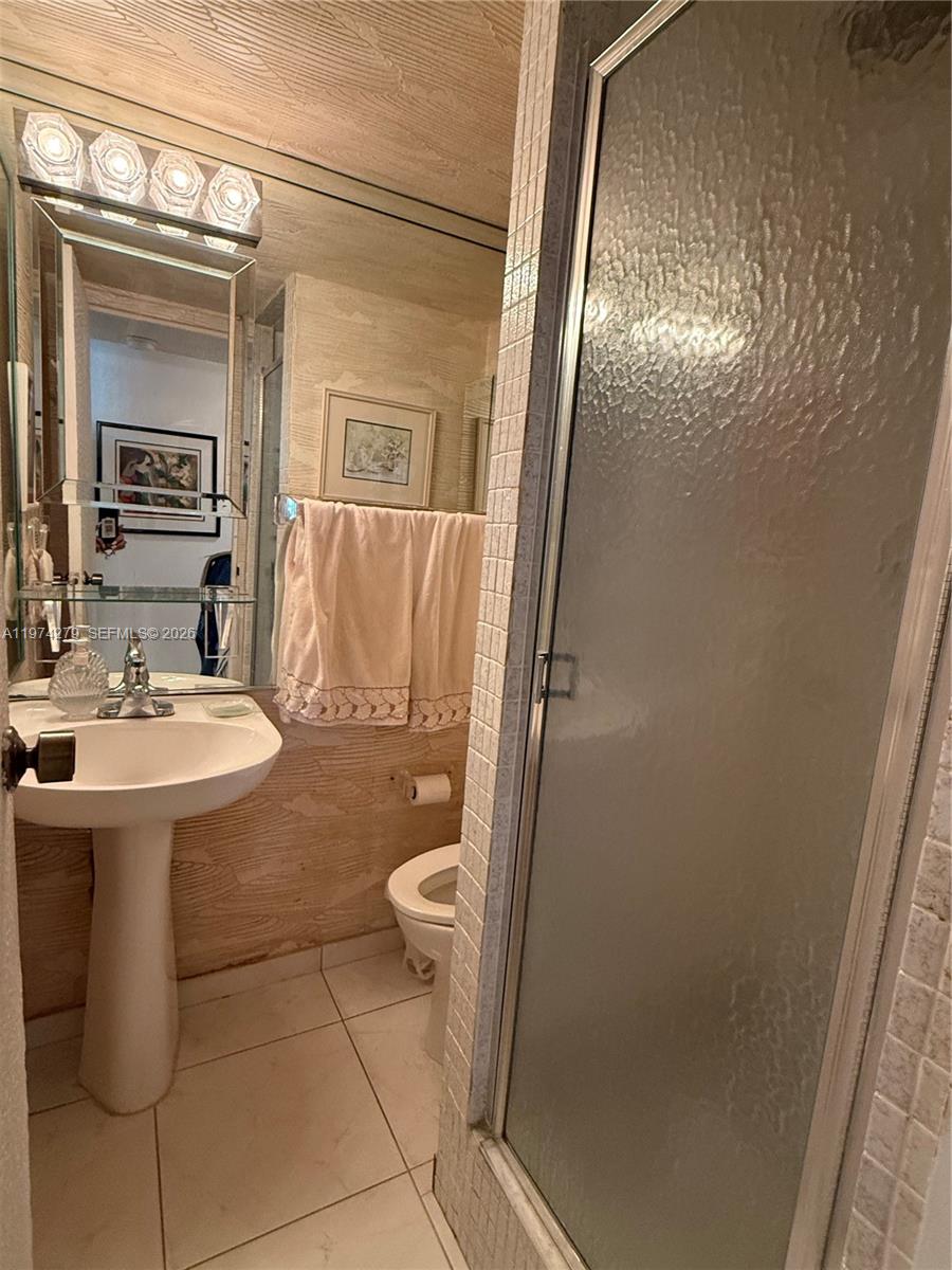 A bathroom features a pedestal sink, a glass-enclosed shower, and a toilet — 1000 Parkview Dr # 1022, Hallandale Beach FL 33009, HALLANDALE BEACH, FL