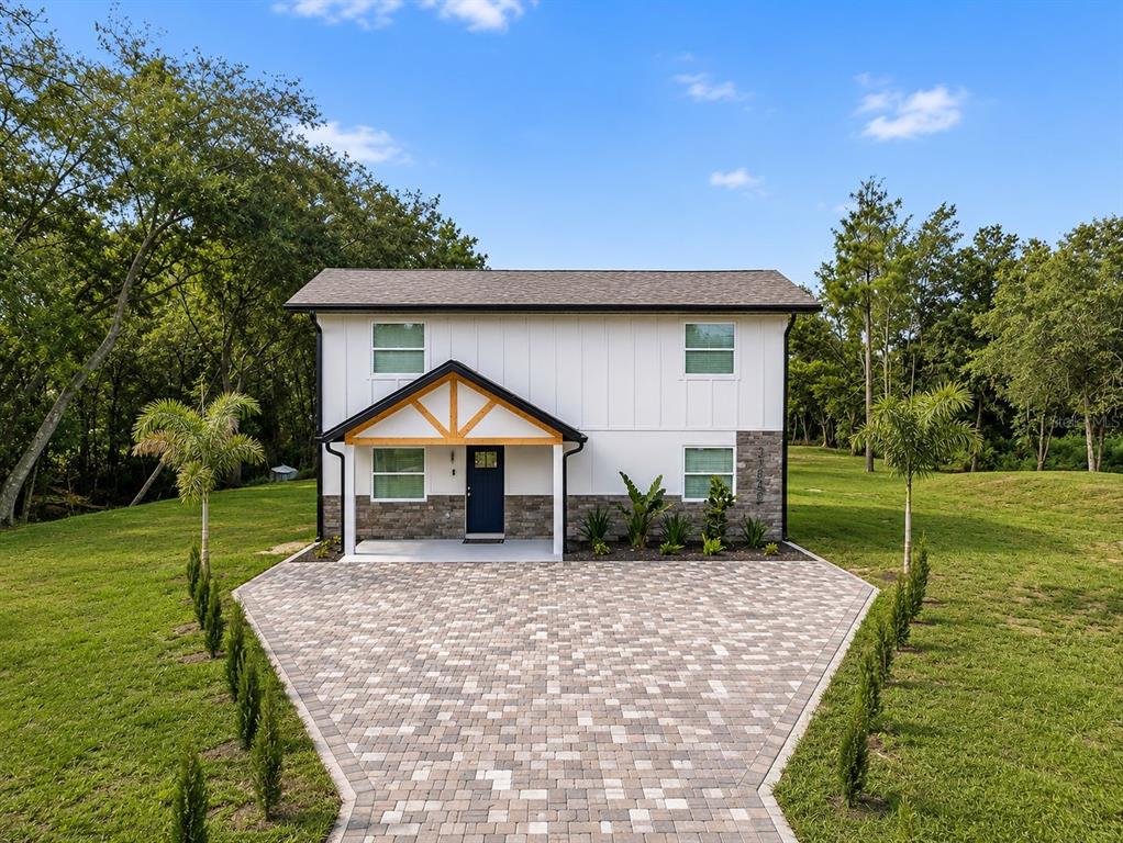 A two-story house with white vertical siding, stone accents, and a paved driveway — 31848 HEDGEROW DRIVE, WESLEY CHAPEL, FL