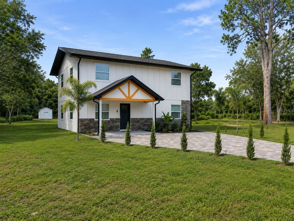 A two-story white house with a stone base and a wooden-accented front porch — 31848 HEDGEROW DRIVE, WESLEY CHAPEL, FL