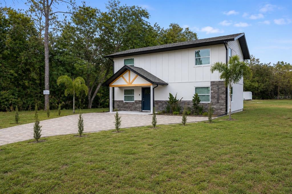 A two-story house with white vertical siding, stone veneer, and a paved driveway — 31848 HEDGEROW DRIVE, WESLEY CHAPEL, FL