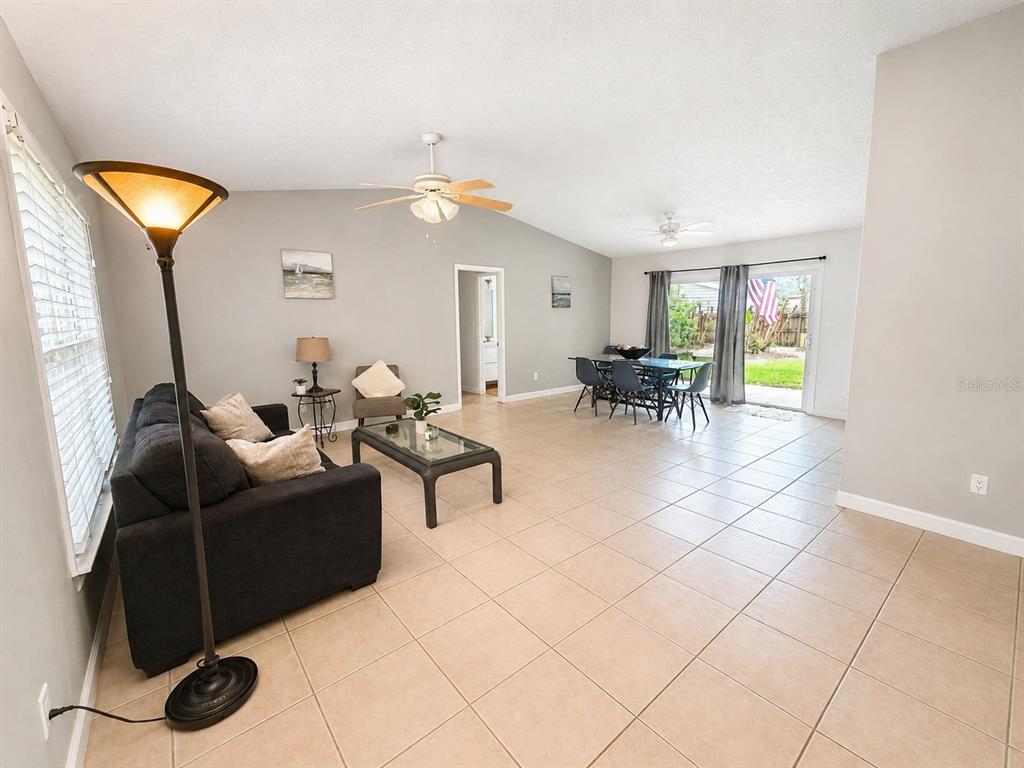 A living and dining area with tile floors, a ceiling fan, and sliding glass doors — 2210 NEEDLE PALM DRIVE, EDGEWATER, FL