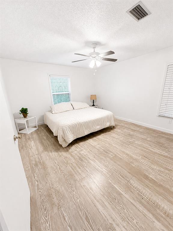 A bedroom features white walls, light wood-look flooring, a ceiling fan, and a bed — 2210 NEEDLE PALM DRIVE, EDGEWATER, FL