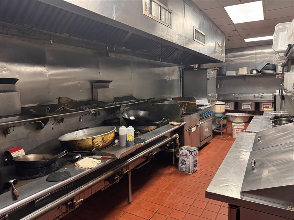 A commercial kitchen features stainless steel equipment, a large exhaust hood, and red tile flooring — 6737 N US 98 HIGHWAY, LAKELAND, FL