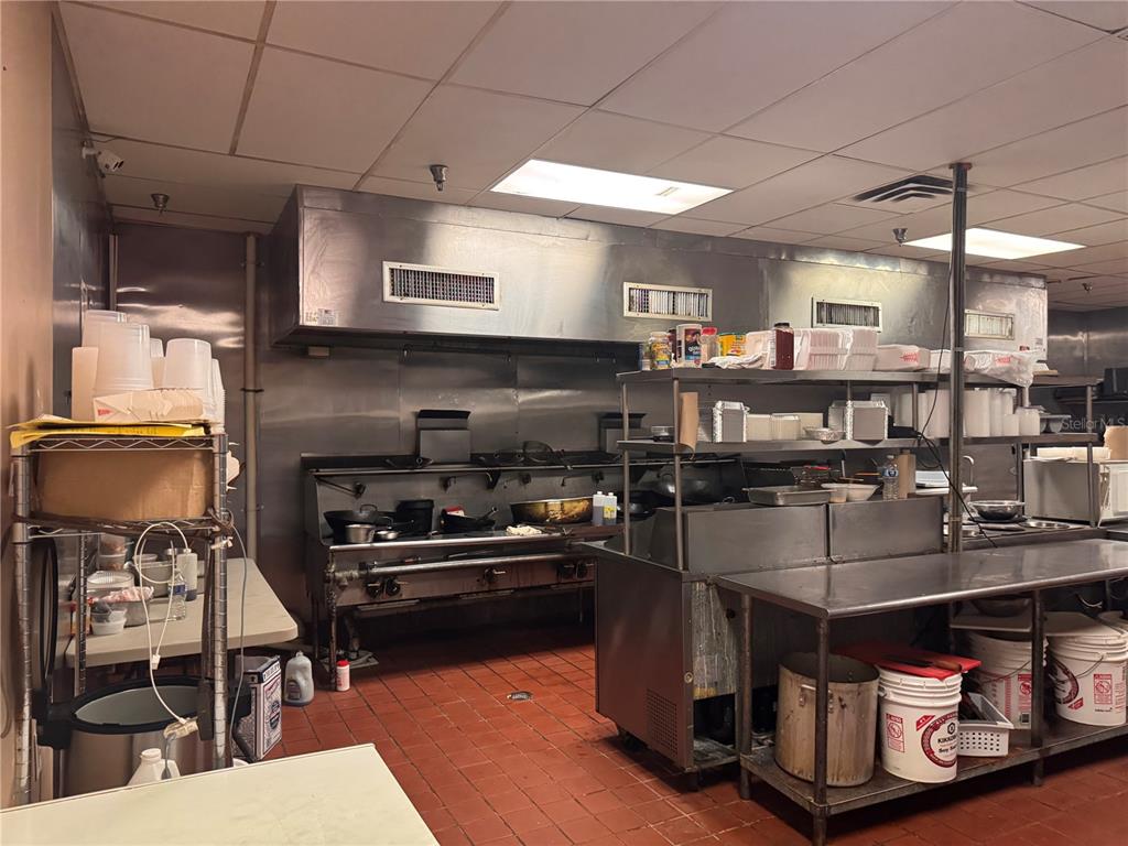 A commercial kitchen features stainless steel equipment, a large ventilation hood, and red tile flooring — 6737 N US 98 HIGHWAY, LAKELAND, FL