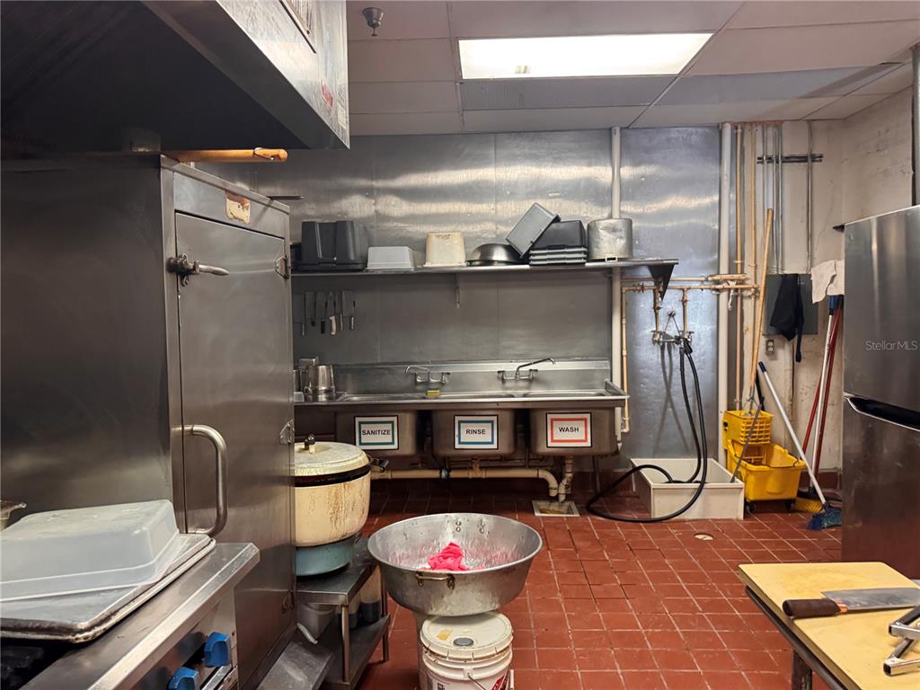 A commercial kitchen features a three-compartment sink, stainless steel equipment, and red tile flooring — 6737 N US 98 HIGHWAY, LAKELAND, FL