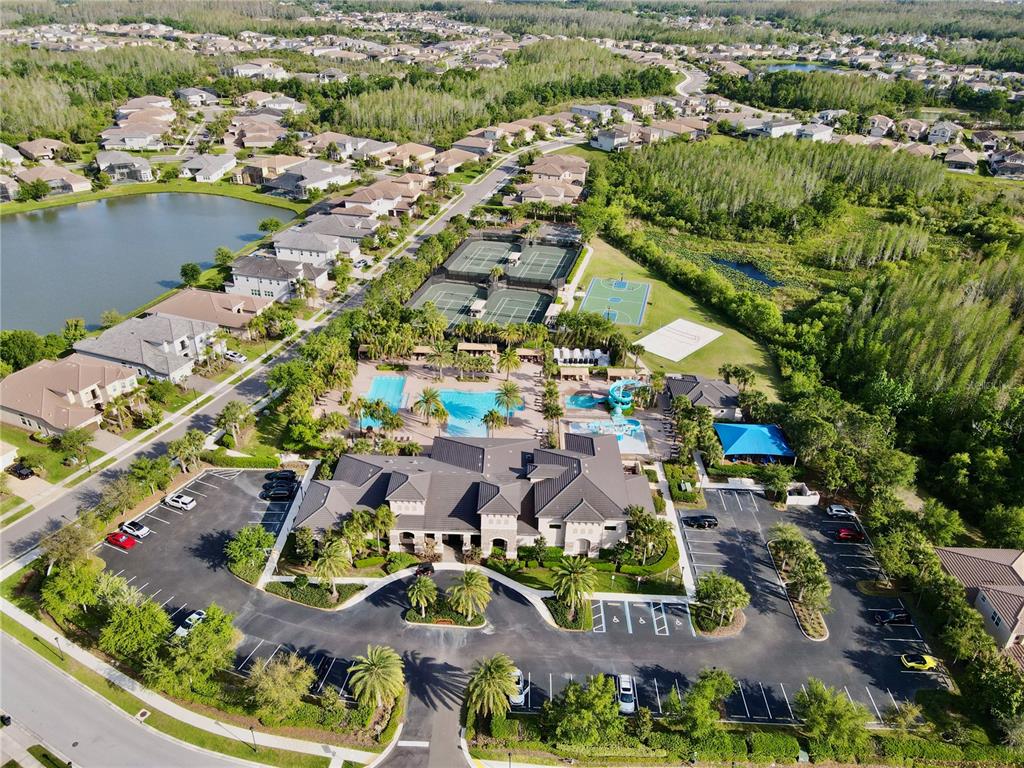 An aerial view shows a community clubhouse with a pool, tennis courts, and parking lot — 30351 TRISTANIA COURT, WESLEY CHAPEL, FL
