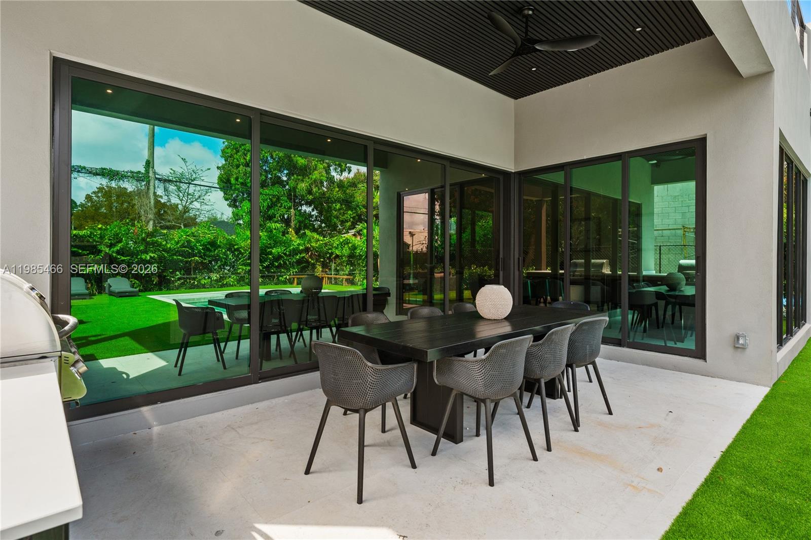 A covered outdoor patio features a dining table with chairs and large sliding glass doors — 245 NE 116th St, Miami FL 33161, MIAMI, FL
