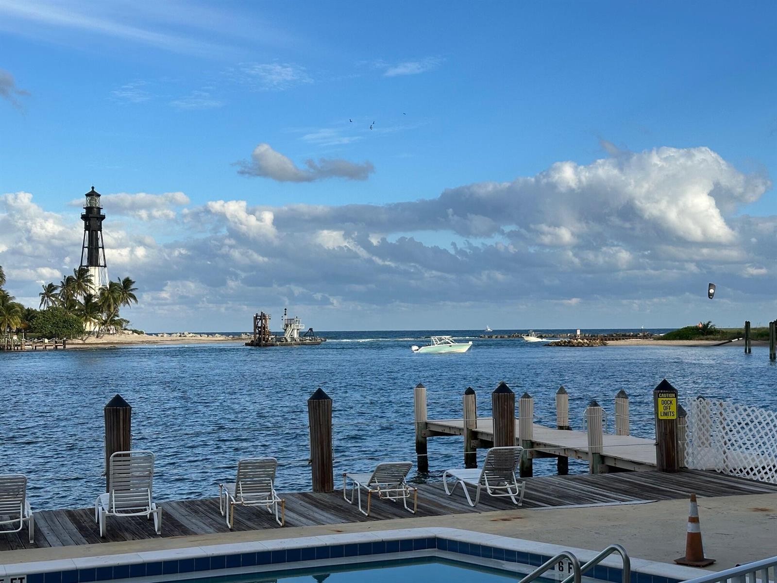 A pool deck with lounge chairs overlooks a dock, a lighthouse, and a waterway — 2508 Bay Drive, Pompano Beach FL 33062, POMPANO BEACH, FL