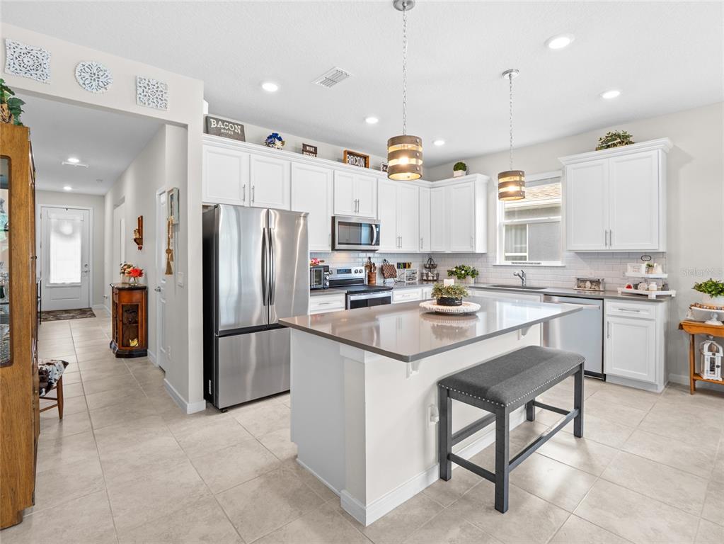 A kitchen features white cabinetry, stainless steel appliances, a center island, and tile flooring — 2209 CANOPY TERRACE BOULEVARD, DELAND, FL