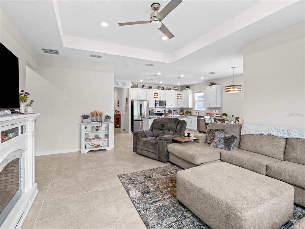 A living room with tile floors, a fireplace, and a sectional sofa opens to a kitchen — 2209 CANOPY TERRACE BOULEVARD, DELAND, FL