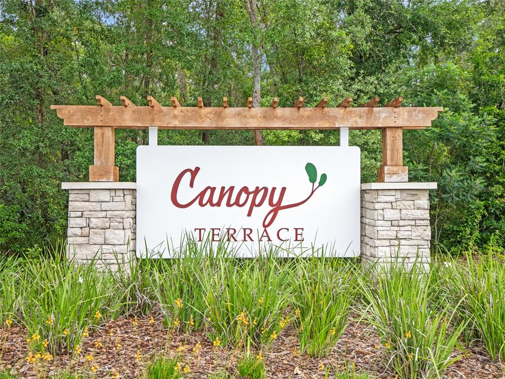 A wooden pergola sits atop a white sign reading Canopy Terrace between two stone pillars — 2209 CANOPY TERRACE BOULEVARD, DELAND, FL