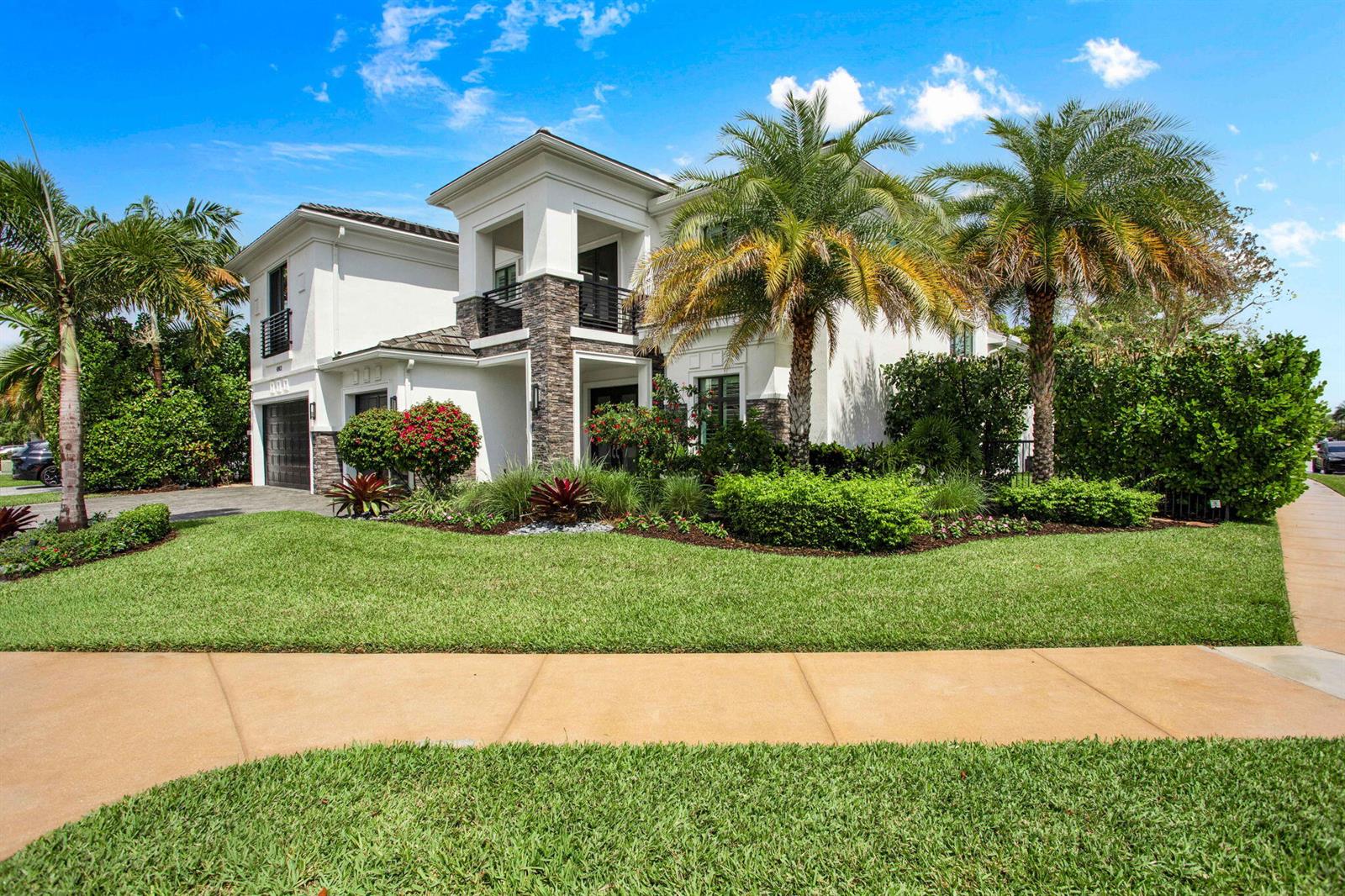 A two-story house with white stucco, stone accents, and palm trees under a blue sky — 6903 NW 28th Avenue, Boca Raton FL 33496, BOCA RATON, FL