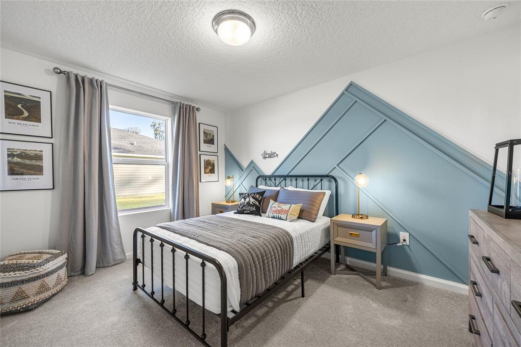 A bedroom features a blue accent wall with geometric molding, a metal bed, and carpet — 16941 NW 144TH STREET, ALACHUA, FL