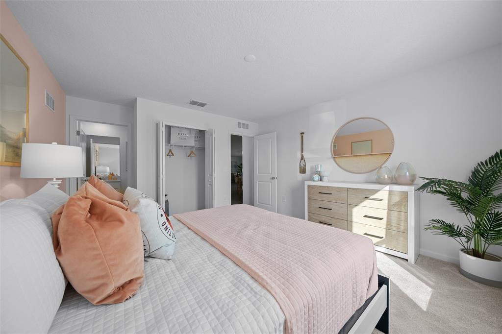 A bedroom features a bed with pink bedding, a wooden dresser, and a round mirror — 16941 NW 144TH STREET, ALACHUA, FL