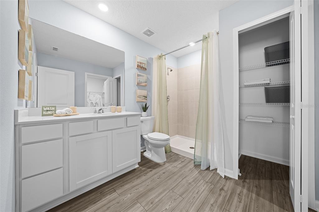 A bathroom features a white vanity, a walk-in shower, a toilet, and an open closet — 16941 NW 144TH STREET, ALACHUA, FL