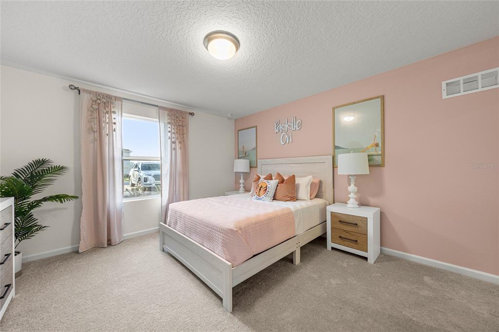 A bedroom features a light wood bed frame, pink accent wall, and two nightstands — 16941 NW 144TH STREET, ALACHUA, FL