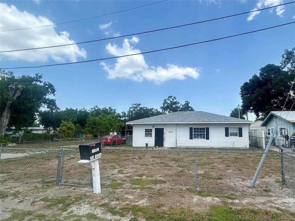 A single-story white house with a chain-link fence sits on a dry, grassy lot — 2628 45TH AVENUE W, BRADENTON, FL