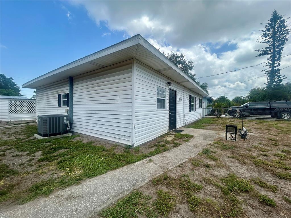 A white, single-story house with horizontal siding, a dark door, and an exterior air conditioning unit — 2628 45TH AVENUE W, BRADENTON, FL
