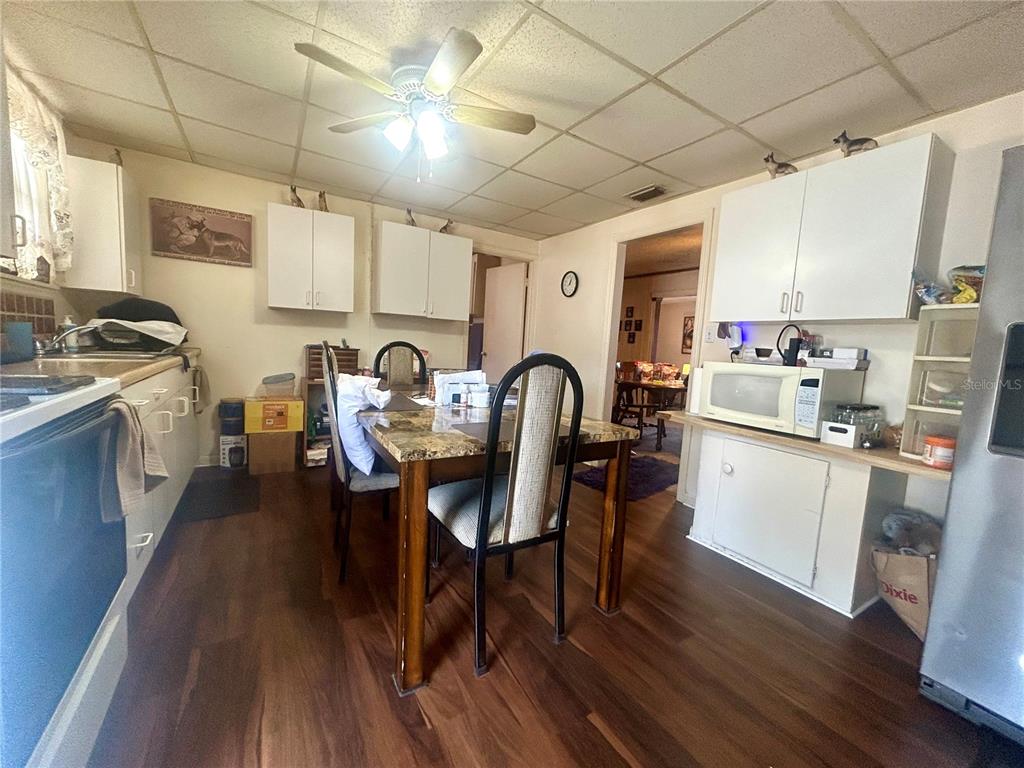 A kitchen with white cabinets, a dining table, and wood-look flooring — 2628 45TH AVENUE W, BRADENTON, FL