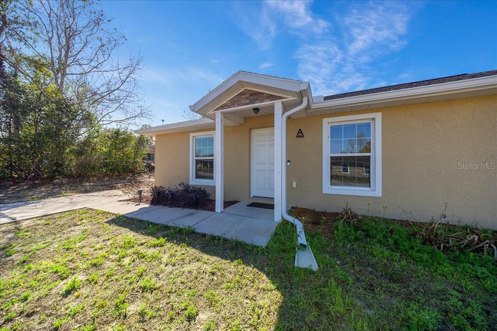 A single-story tan stucco house with a white front door and a covered entryway — 5364 NW 2ND PLACE, OCALA, FL
