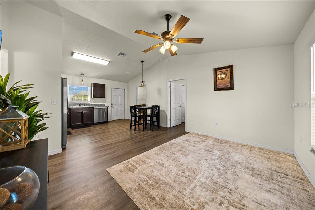 An open-concept living and dining area features wood-look flooring, a ceiling fan, and kitchen — 5364 NW 2ND PLACE, OCALA, FL