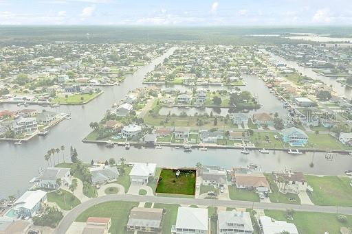 An aerial view shows a vacant waterfront lot highlighted in a residential canal community — PARADISE CIRCLE, HERNANDO BEACH, FL