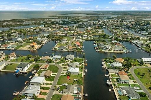 An aerial view shows a waterfront residential neighborhood with canals and houses on grassy lots — PARADISE CIRCLE, HERNANDO BEACH, FL