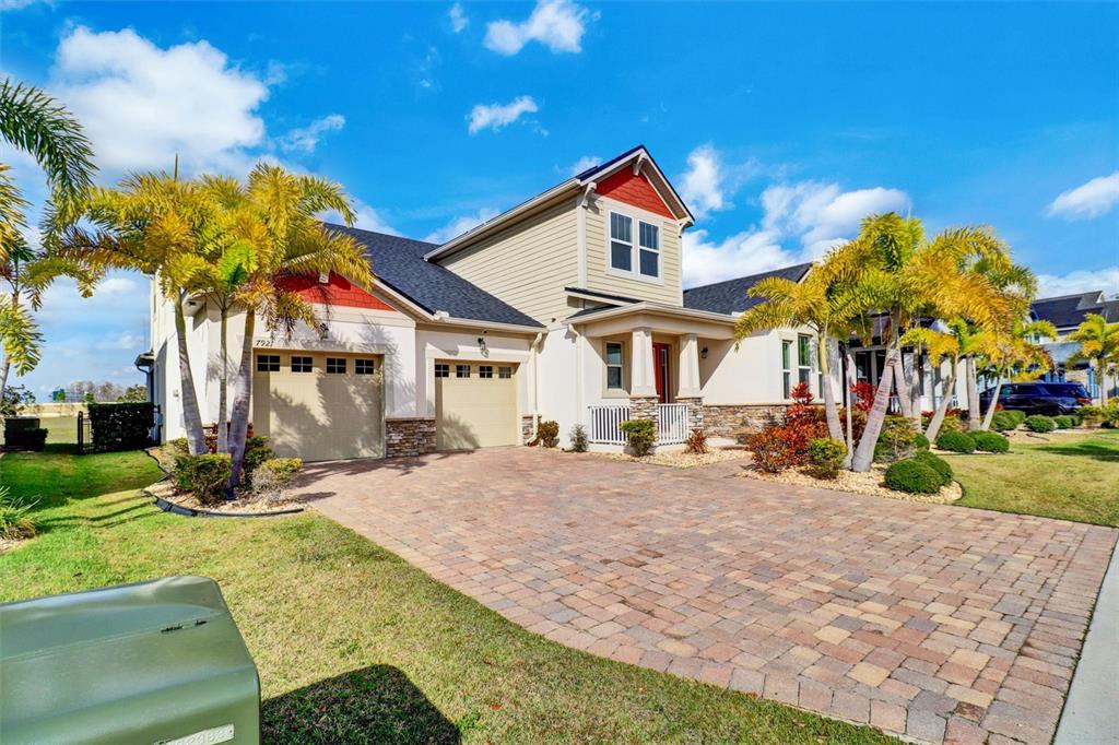 A two-story house with a paved driveway, two garage doors, and several palm trees — 7921 CORKFIELD AVENUE, ORLANDO, FL