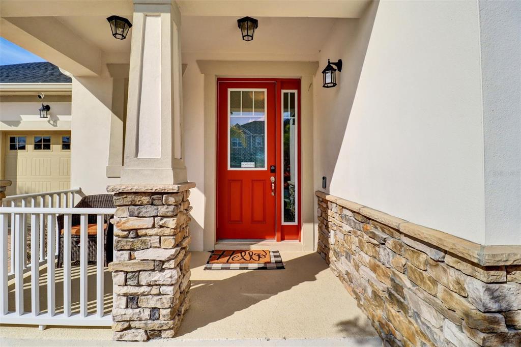 A bright red front door sits on a covered porch with stone accents and railings — 7921 CORKFIELD AVENUE, ORLANDO, FL