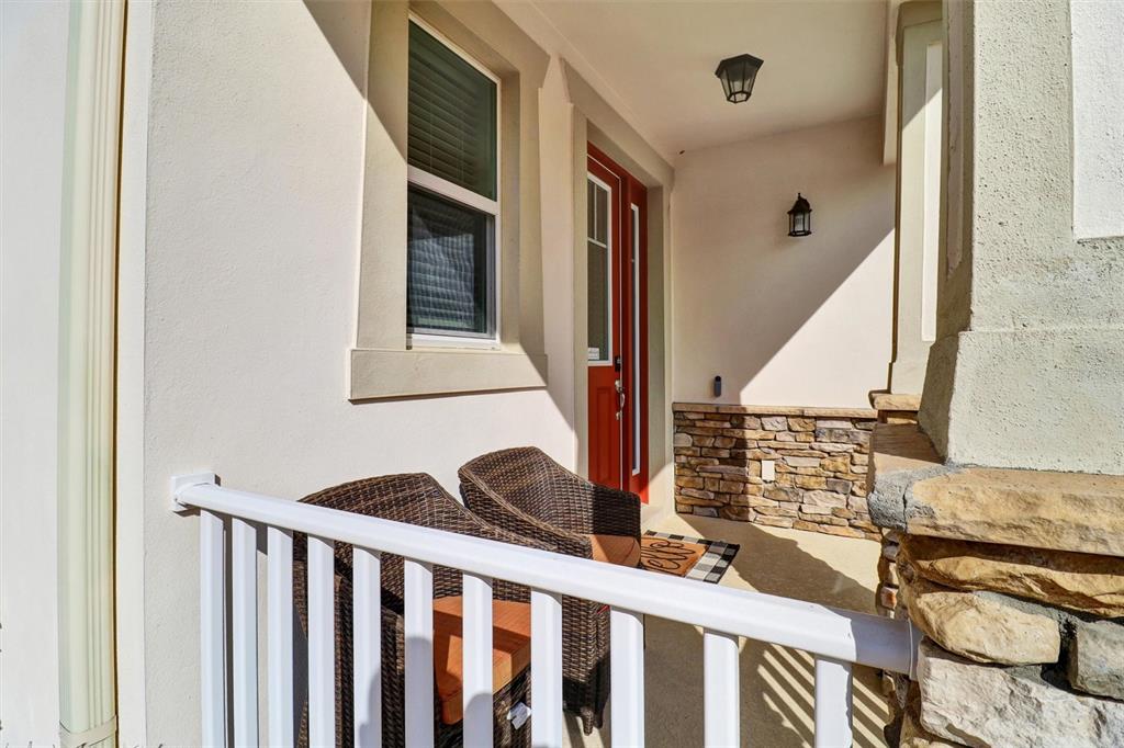 A covered front porch features a red door, stone siding, and two wicker chairs — 7921 CORKFIELD AVENUE, ORLANDO, FL