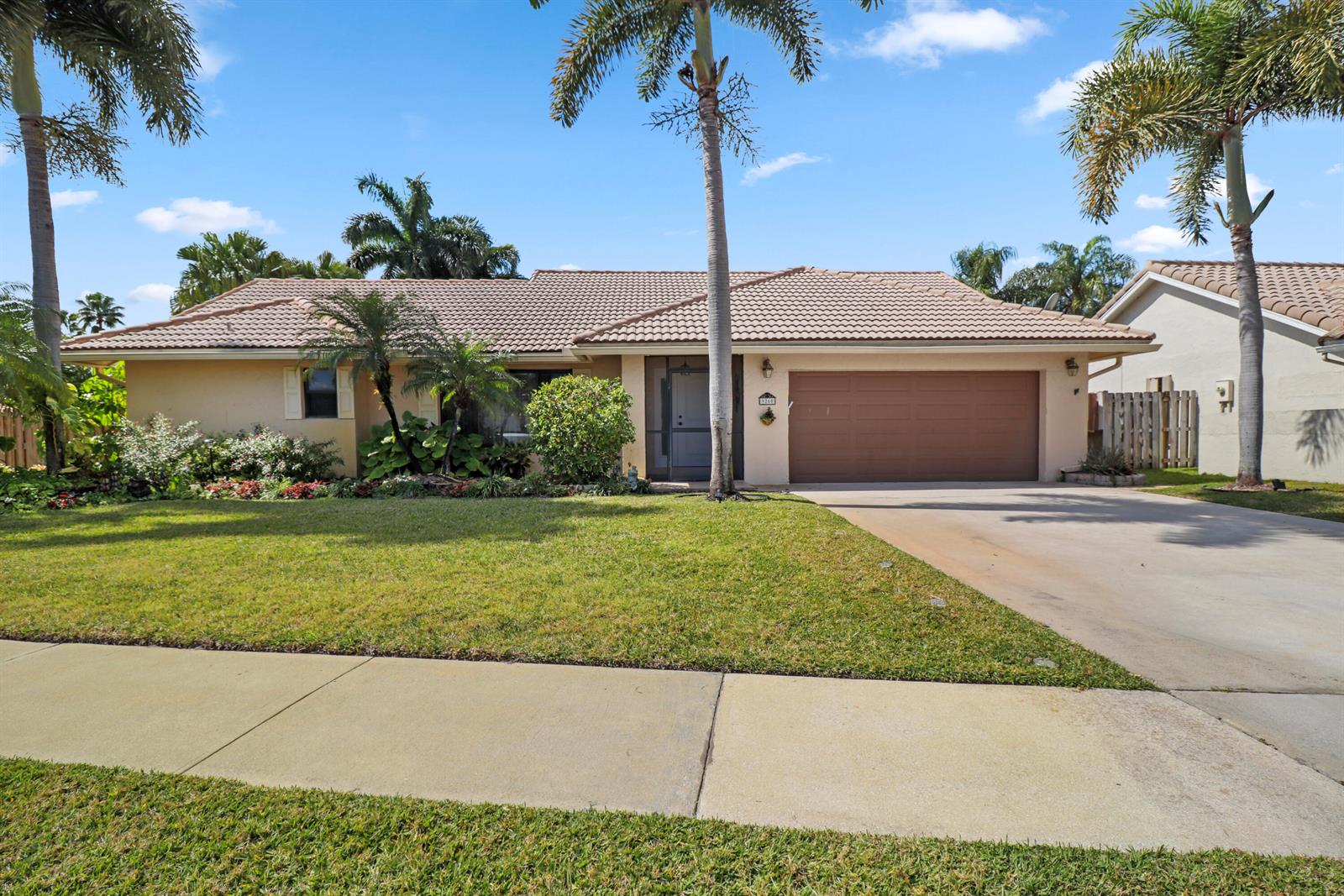 A single-story house with a brown garage door, tiled roof, and palm trees in front — 9260 Laurel Green Drive, Boynton Beach FL 33437, BOYNTON BEACH, FL