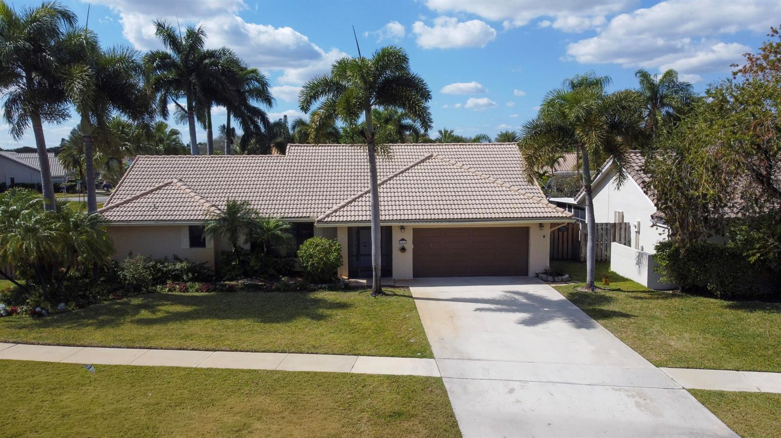 An aerial view of a single-story house with a tiled roof, palm trees, and driveway — 9260 Laurel Green Drive, Boynton Beach FL 33437, BOYNTON BEACH, FL