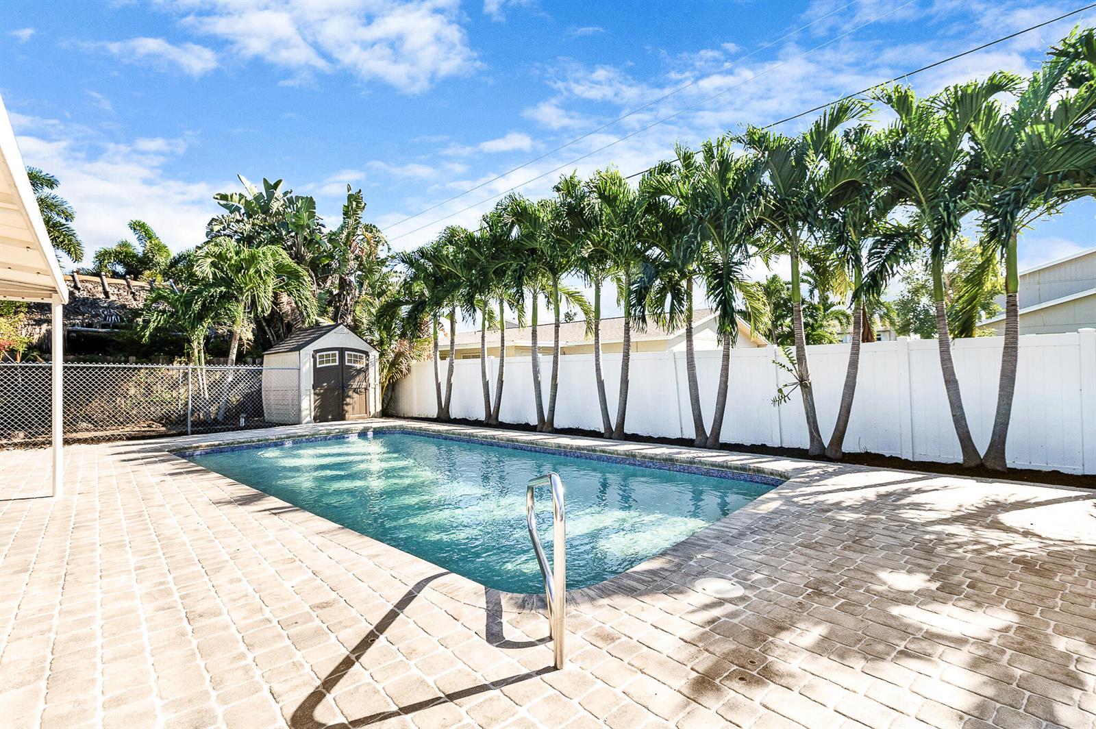 A rectangular swimming pool with a brick paver deck and palm trees in a backyard — 912 SE 8th Court, Deerfield Beach FL 33441, DEERFIELD BEACH, FL
