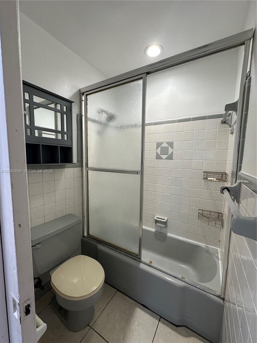 A bathroom features a gray bathtub, a sliding glass shower door, and a toilet — 819 NE 8th St # 2, Hallandale Beach FL 33009, HALLANDALE BEACH, FL