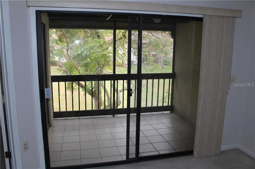A sliding glass door opens onto a screened-in balcony with tiled flooring and a railing — 2906 S SEMORAN BOULEVARD UNIT 2, ORLANDO, FL