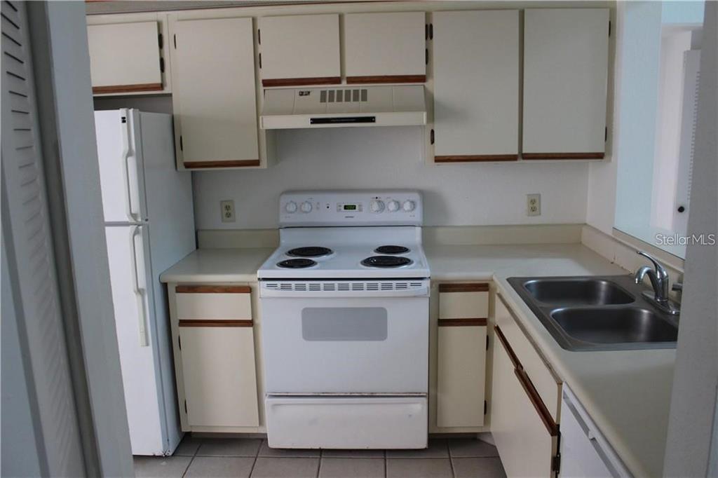 A kitchen features white appliances, light-colored cabinets, and a double-basin stainless steel sink — 2906 S SEMORAN BOULEVARD UNIT 2, ORLANDO, FL