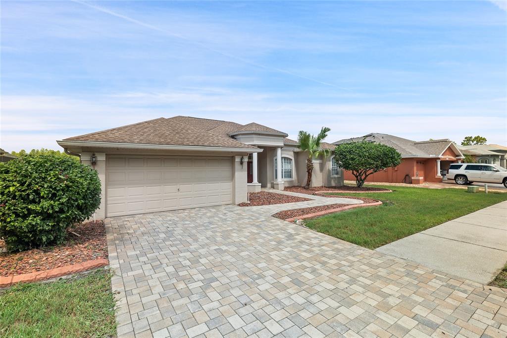 A single-story house with a paved driveway, two-car garage, and a landscaped front yard — 7154 MELOGOLD CIRCLE, LAND O LAKES, FL