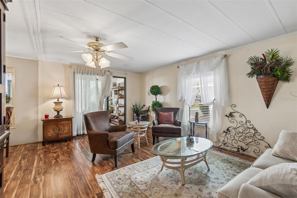 A living room features wood-look flooring, a ceiling fan, and a glass-topped coffee table — 12501 ULMERTON ROAD UNIT 175, LARGO, FL