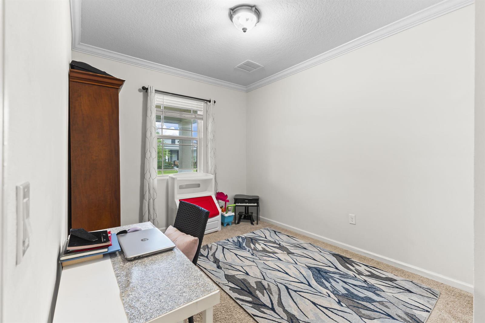 A home office features a desk, a large area rug, and a tall wooden cabinet — 1465 Bruntsfield Terrace, Vero Beach FL 32966, VERO BEACH, FL
