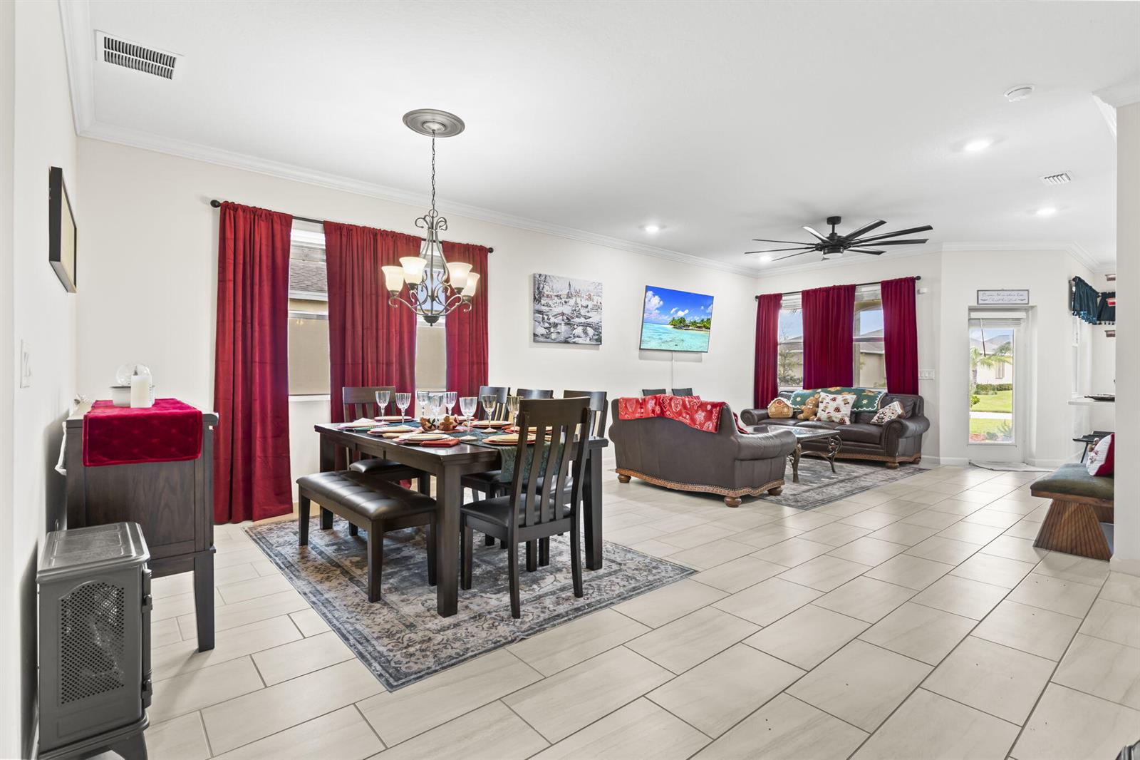 An open-concept dining and living area features tile flooring, dark wood furniture, and red curtains — 1465 Bruntsfield Terrace, Vero Beach FL 32966, VERO BEACH, FL