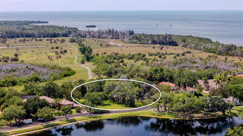 An aerial view shows a wooded lot circled in white near a pond and coastline — 1846 AMBERWYND CIRCLE W, PALMETTO, FL