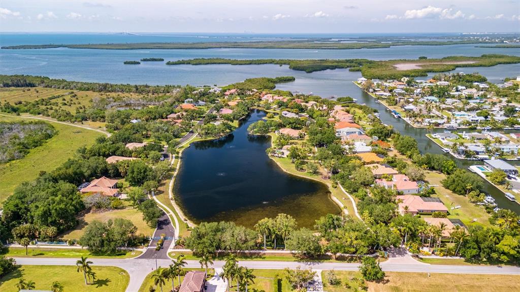 An aerial view shows a residential neighborhood surrounding a lake near a coastal bay — 1846 AMBERWYND CIRCLE W, PALMETTO, FL