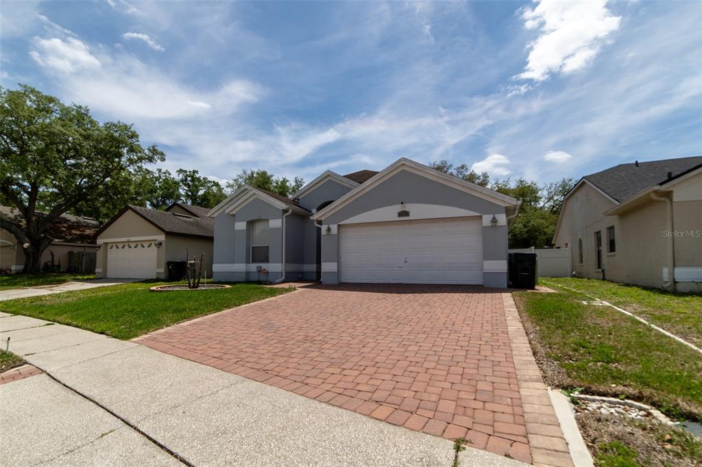 A single-story house with a gray exterior, a two-car garage, and a brick paver driveway — 1352 WOODFIELD OAKS DRIVE, APOPKA, FL