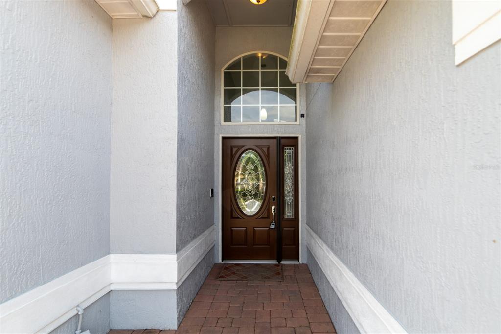 A covered entryway features a brown front door with a glass insert and a transom window — 1352 WOODFIELD OAKS DRIVE, APOPKA, FL