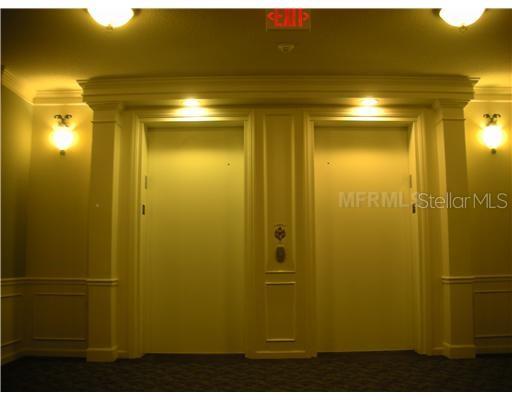 A hallway view shows two closed elevator doors framed by decorative molding and wall sconces — 3368 ROBERT TRENT JONES DRIVE UNIT 40208, ORLANDO, FL