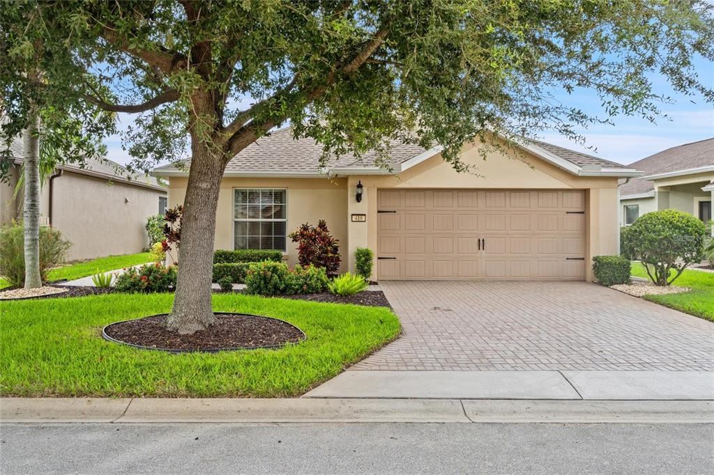 A single-story house with a beige stucco exterior, a two-car garage, and a large tree — 418 DEL SOL AVENUE, DAVENPORT, FL